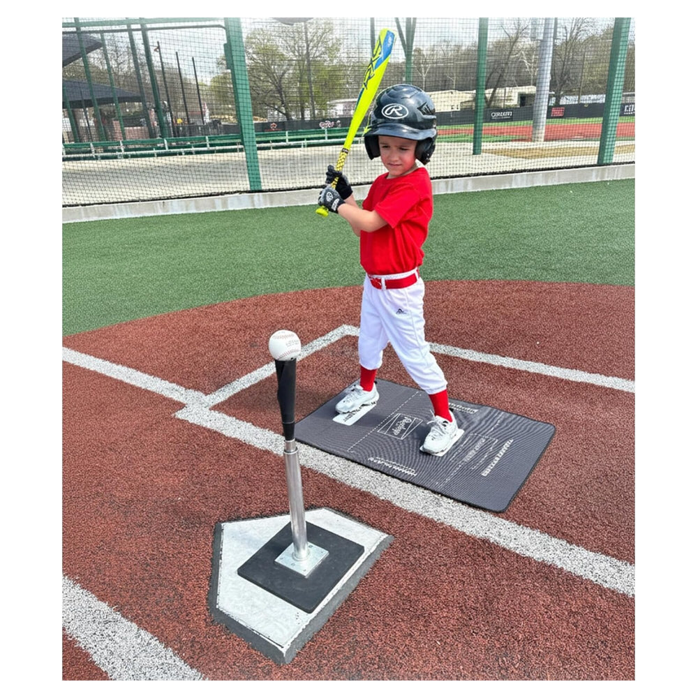 Nino bateando desde el tee parado sobre el tapete de entrenamiento Rawlings junto al home